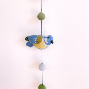 Close up of a felt blue tit bird on the garland, showing blue, yellow, and green wool