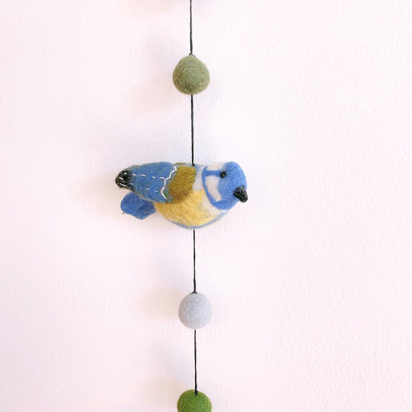 Close up of a felt blue tit bird on the garland, showing blue, yellow, and green wool
