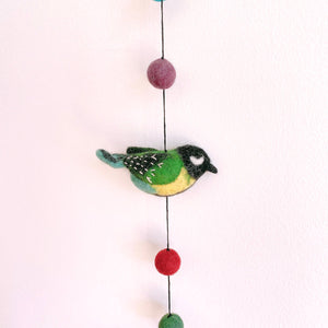 Close up of a felt great tit bird on the garland, showing green and yellow wool detail