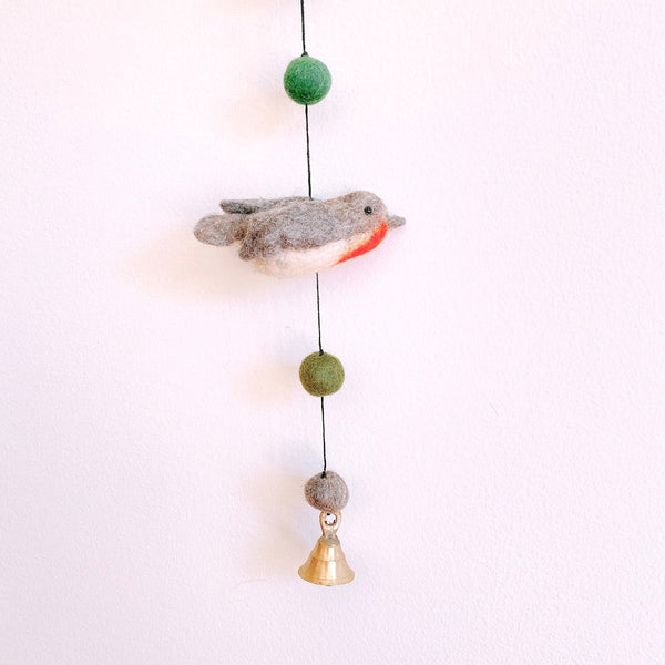 Close up of a felt robin bird on the garland, hanging near the copper bell at the end