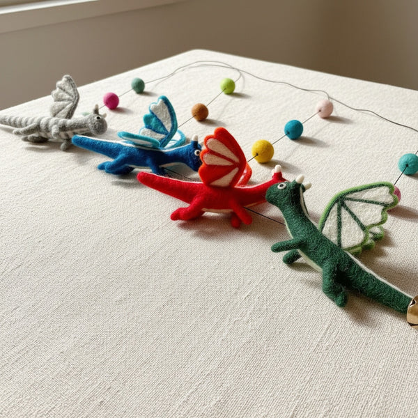 Close up of a felt dragon garland section on linen, showing the wool texture and pom poms