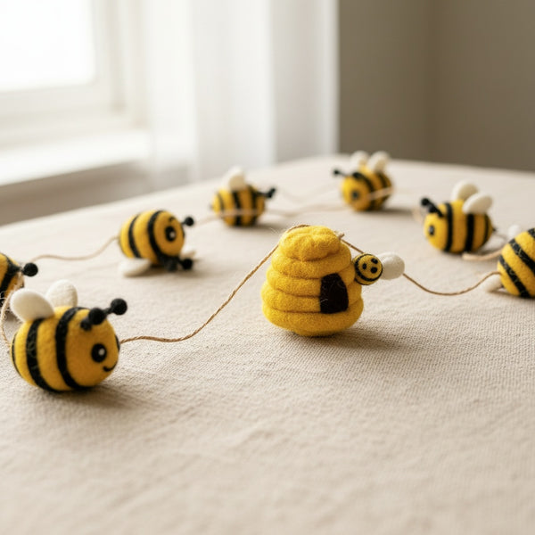 Close-up of felt bee garland on light linen, showing the wool felt texture and bee details