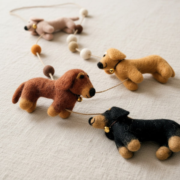 Close-up of the felt dachshund garland on linen fabric, showing the soft felt texture and stitching.