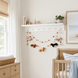 Felt dachshund garland hanging above a crib in a calm, sunlit nursery with neutral walls.