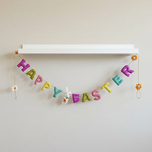 Felt Happy Easter garland hanging along a white nursery shelf in soft daylight