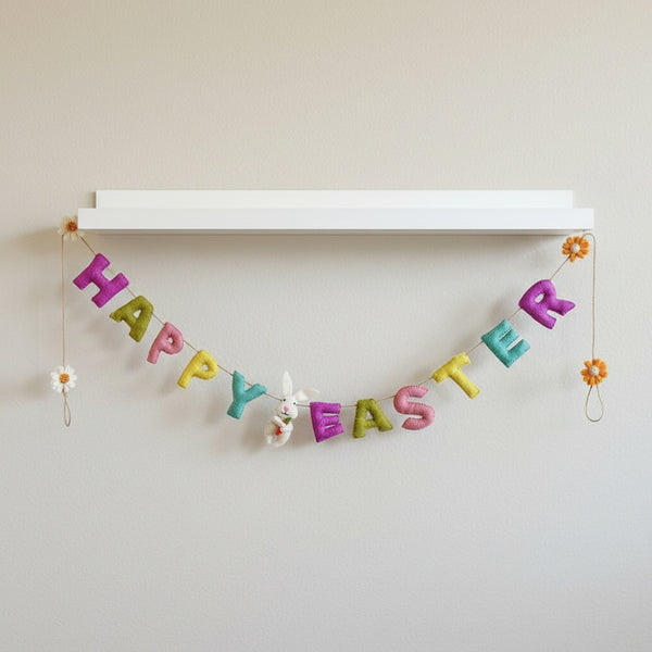 Felt Happy Easter garland hanging along a white nursery shelf in soft daylight