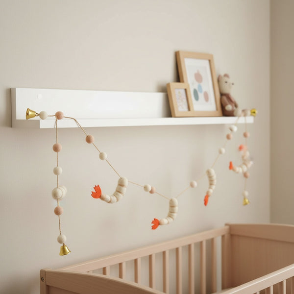 This felt shrimp garland draped along a white nursery shelf, adding a playful touch above a crib