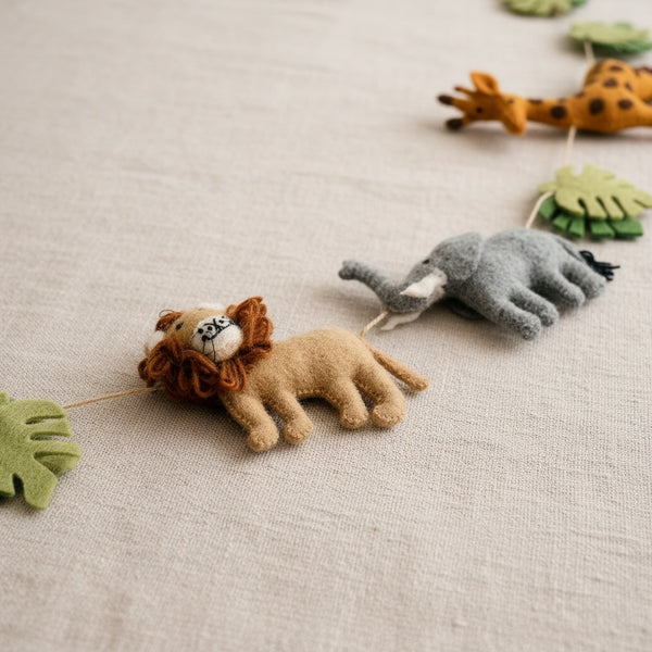 Close-up of felt jungle animal garland on linen showing wool texture and jute thread