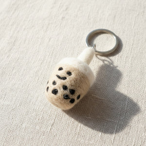 Close-up of a felt boba tea keychain on light linen, showing hand-stitched felt texture