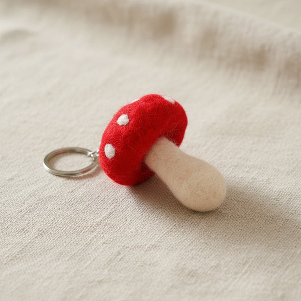 Close-up of a felt mushroom keychain on linen, showing the wool's soft felted texture.