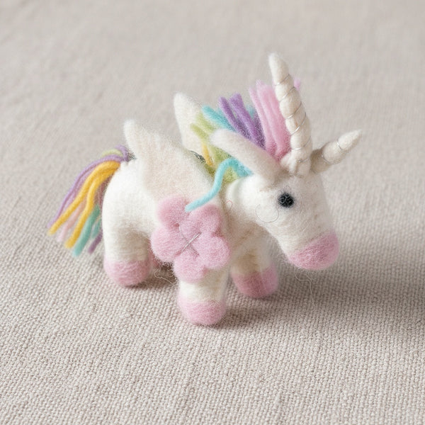 Close-up of the pastel unicorn felt keychain resting on linen, showing its soft wool texture.