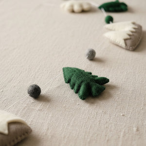 Close up of felt garland texture showing mountain and pine tree shapes on a light linen surface