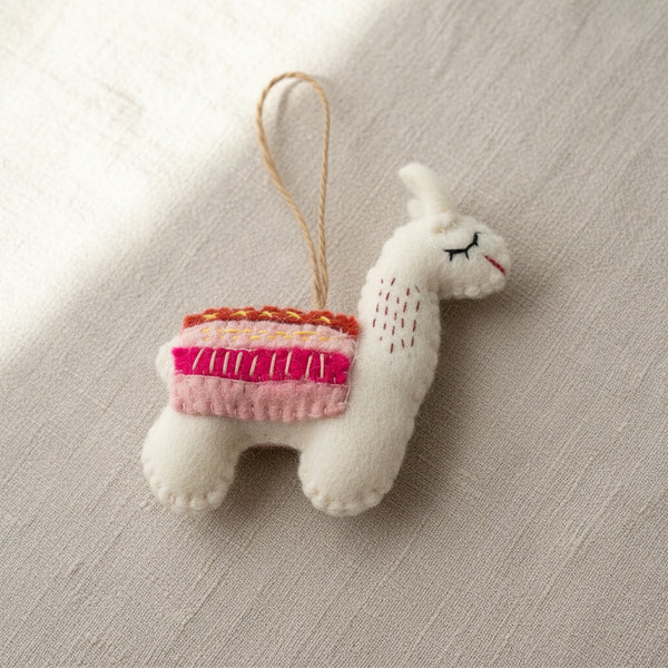 Close-up of the felt llama ornament's wool texture and stitched saddle on linen fabric