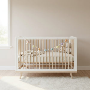 Felt pastel mushroom garland draped along a white nursery shelf in soft daylight.