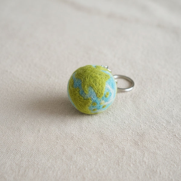 Close-up of the felt planet keychain showing its needle felted wool texture and tie dye pattern