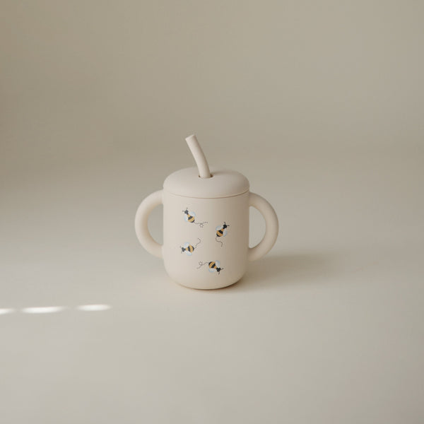 Silicone training cup with straw, angled view, perfect for toddlers learning to drink independently.