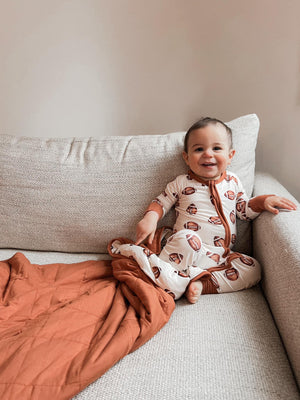 Football print quilted bamboo blanket for babies, 1.0 Tog, cozy swaddle and baby blanket, angle view.