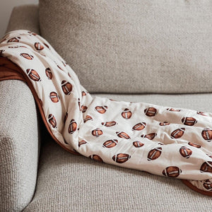 Football print quilted bamboo blanket - 1.0 Tog, perfect for swaddling and keeping babies cozy. Angle view.