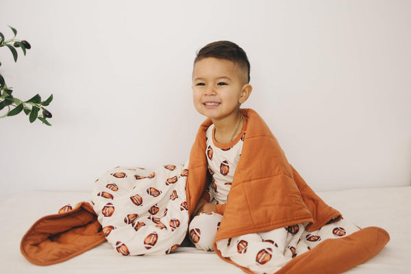 Football print quilted bamboo blanket for babies, 1.0 Tog, shown at angle 3. Perfect for swaddling and comfort.