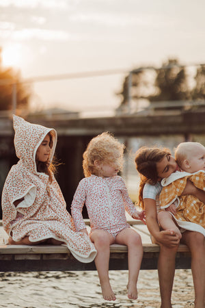 Organic cotton bathing towel poncho for babies in Sunset Meadow design, angled view showcasing softness and style.