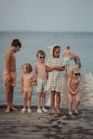 Baby swim trunks in buckwheat plaid, UPF protected and made from recycled materials, angle 14 view.