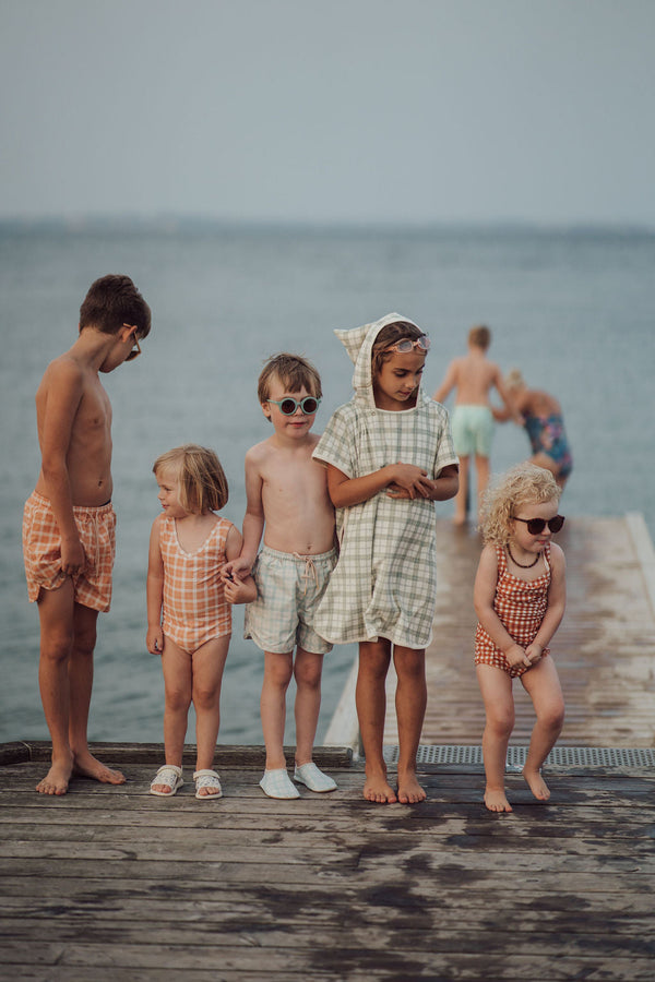 Baby swim trunks in buckwheat plaid, UPF protected and made from recycled materials, angle 14 view.