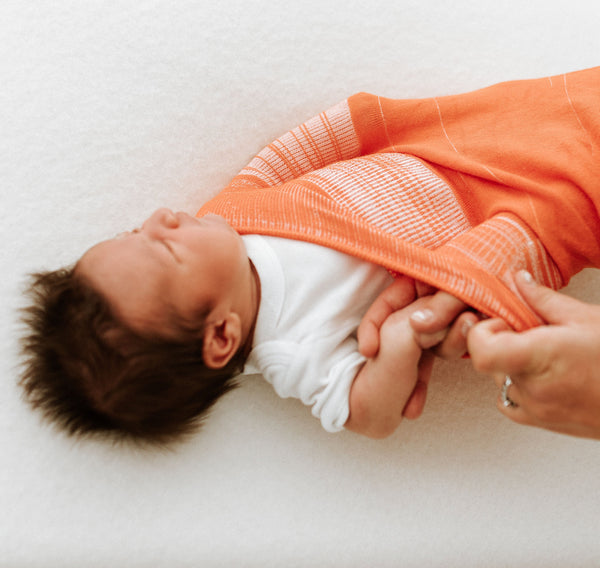 Orange Swaddle Sleep Sack from Swaddelini, shown at angle 2, perfect for cozy and secure baby sleep.