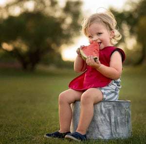 Solid Candy Apple Red Minimalist Bapron for babies, angled view showcasing its stylish design and vibrant color.
