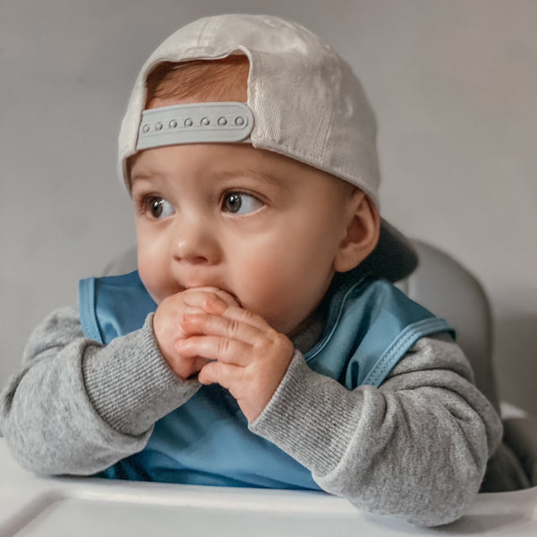 Solid dusty blue minimalist bapron for babies, angled view showcasing its stylish and functional design.