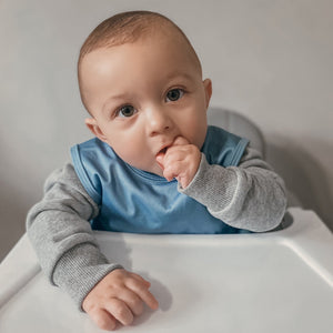 Solid dusty blue minimalist bapron for babies, angled view showcasing its stylish design and practical features.
