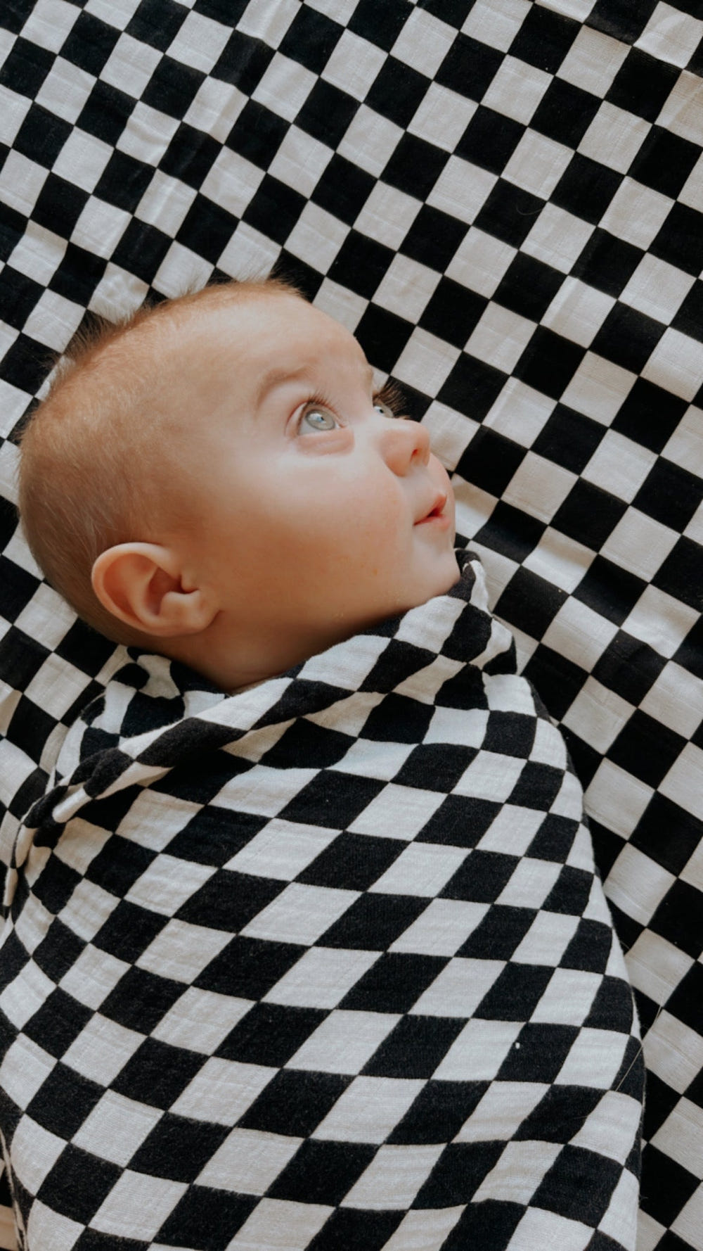 Black and white checkerboard muslin swaddle for babies, soft and breathable for comfort and style.