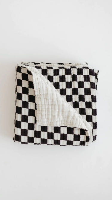 Black and white checkerboard muslin quilt for babies, soft and stylish blanket for nursery decor.