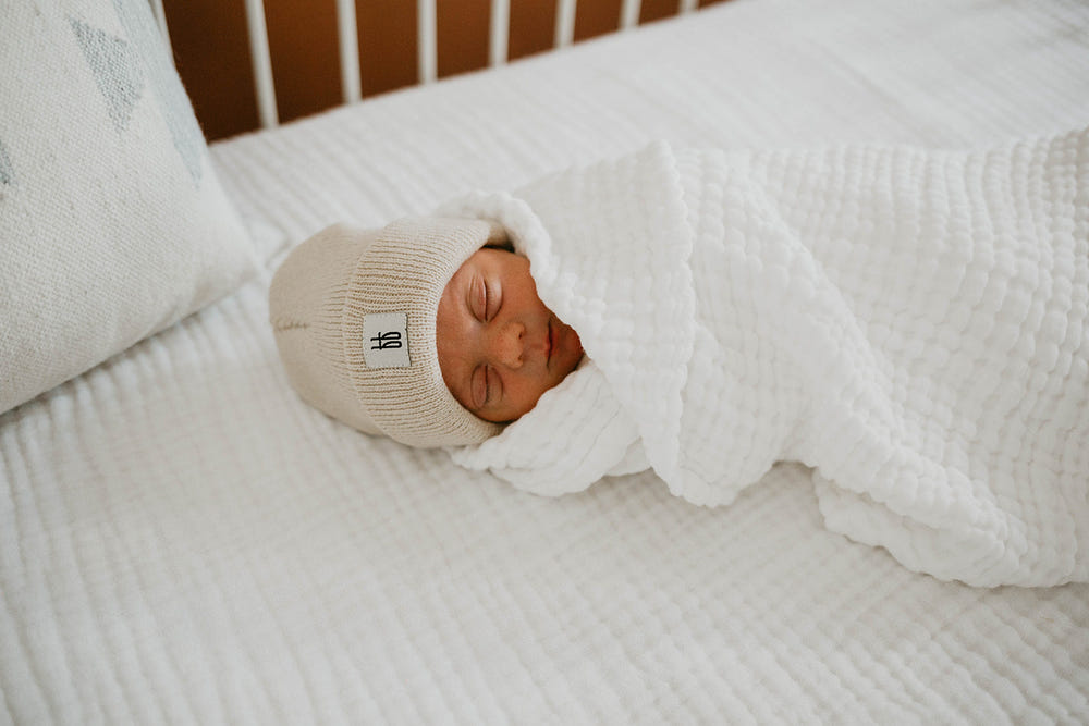 Soft cloud-patterned crib sheet for babies, perfect for swaddling and nursery decor.