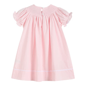 Light pink daisy smocked bishop dress for babies, angle view showcasing delicate design and soft fabric.