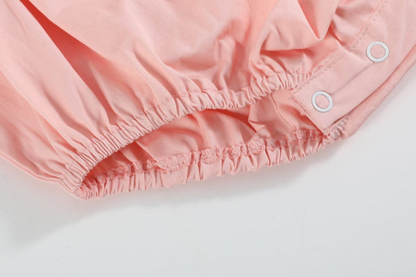 Light pink Easter smocked flutter romper for babies, showcasing a cute design from an angled view.