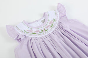 Light purple bunnies smocked bishop dress for babies, angle view showcasing adorable design and craftsmanship.