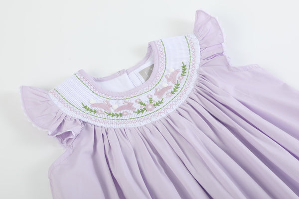 Light purple bunnies smocked bishop dress for babies, angle view showcasing adorable design and craftsmanship.