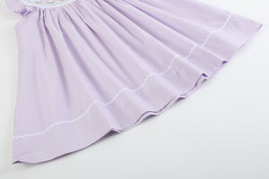 Light purple bunnies smocked bishop dress for babies, angle view showcasing design and details.
