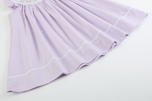 Light purple bunnies smocked bishop dress for babies, angle view showcasing design and details.