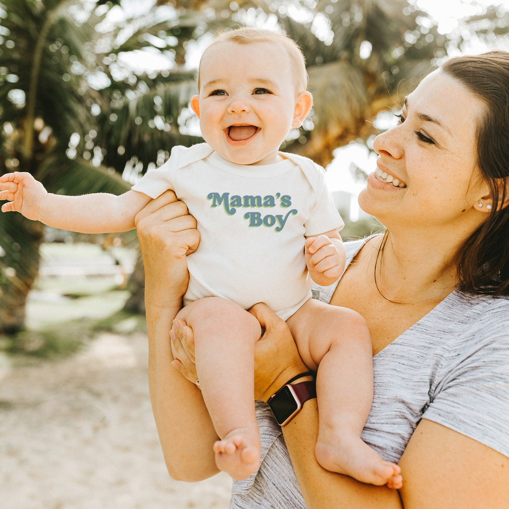 "Graphic short sleeve bodysuit for babies featuring 'Mama's Boy' design."