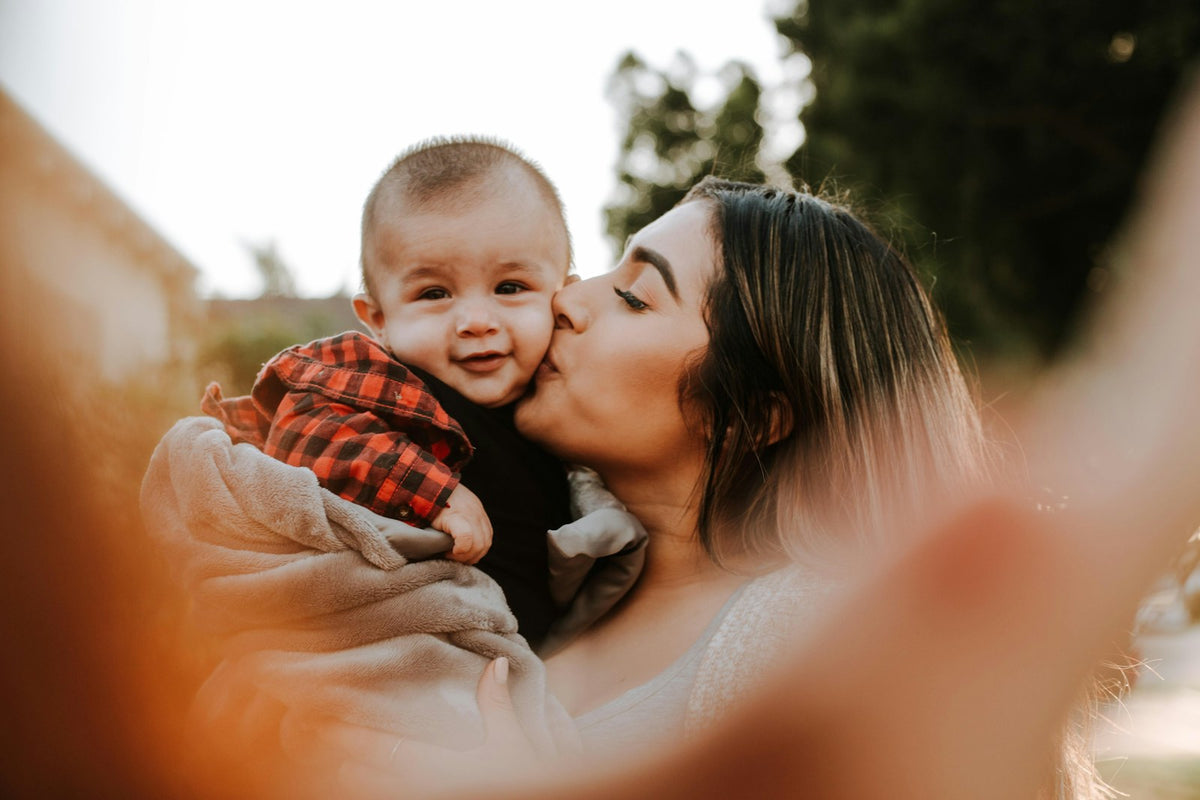 Smiling mom kissing her happy baby on the cheek