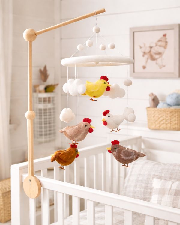 Felt farm animal baby mobile hanging over a white crib