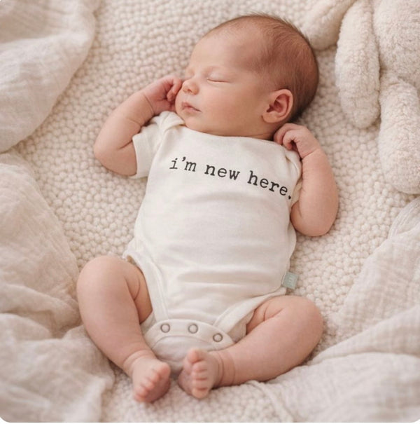 Graphic bodysuit for babies with "I'm New Here" design, short sleeves, angle view. Perfect for newborn outfits.