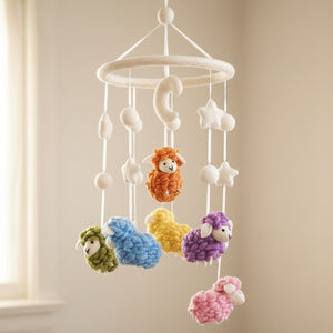 Low angle close up of the handmade felt sheep mobile against a warm, blurred cream wall