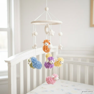 Pastel felt sheep mobile hanging above a light wood crib in a calm, sunlit nursery