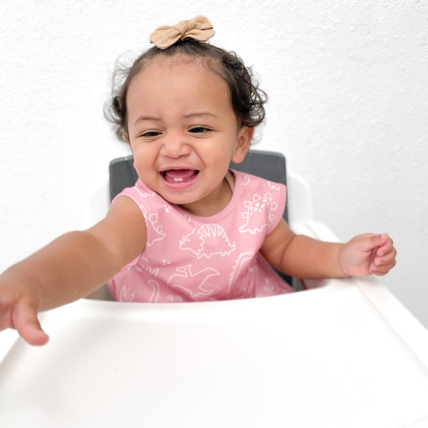 Blush Dino Friends Bapron for babies, stylish and practical, angled view showcasing its cute design and functionality.