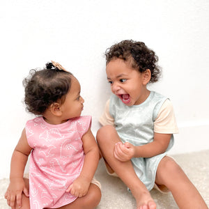 Blush Dino Friends Bapron for babies, stylish and functional, angled view showcasing playful dinosaur design.