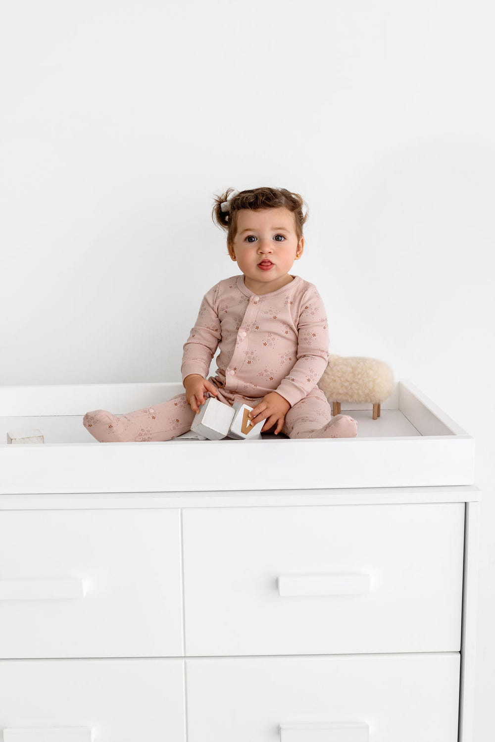 Dusty pink star print footie for babies, perfect for sleep and cozy bedding.
