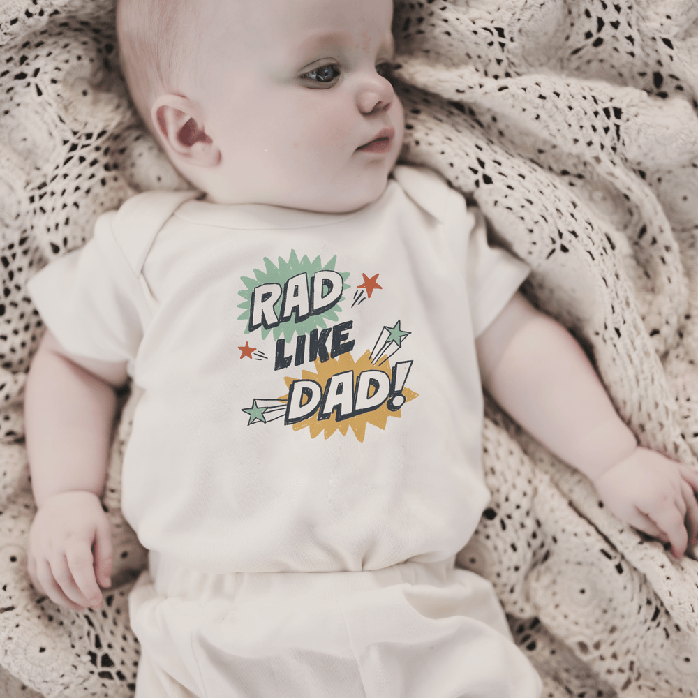 "Graphic short sleeve bodysuit for babies - 'Rad Like Dad' explosion design, perfect for stylish little ones."