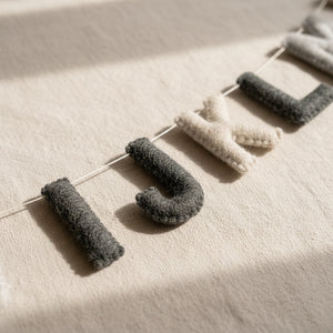 Close-up of felt alphabet letters on a linen surface showing wool felt texture in natural light